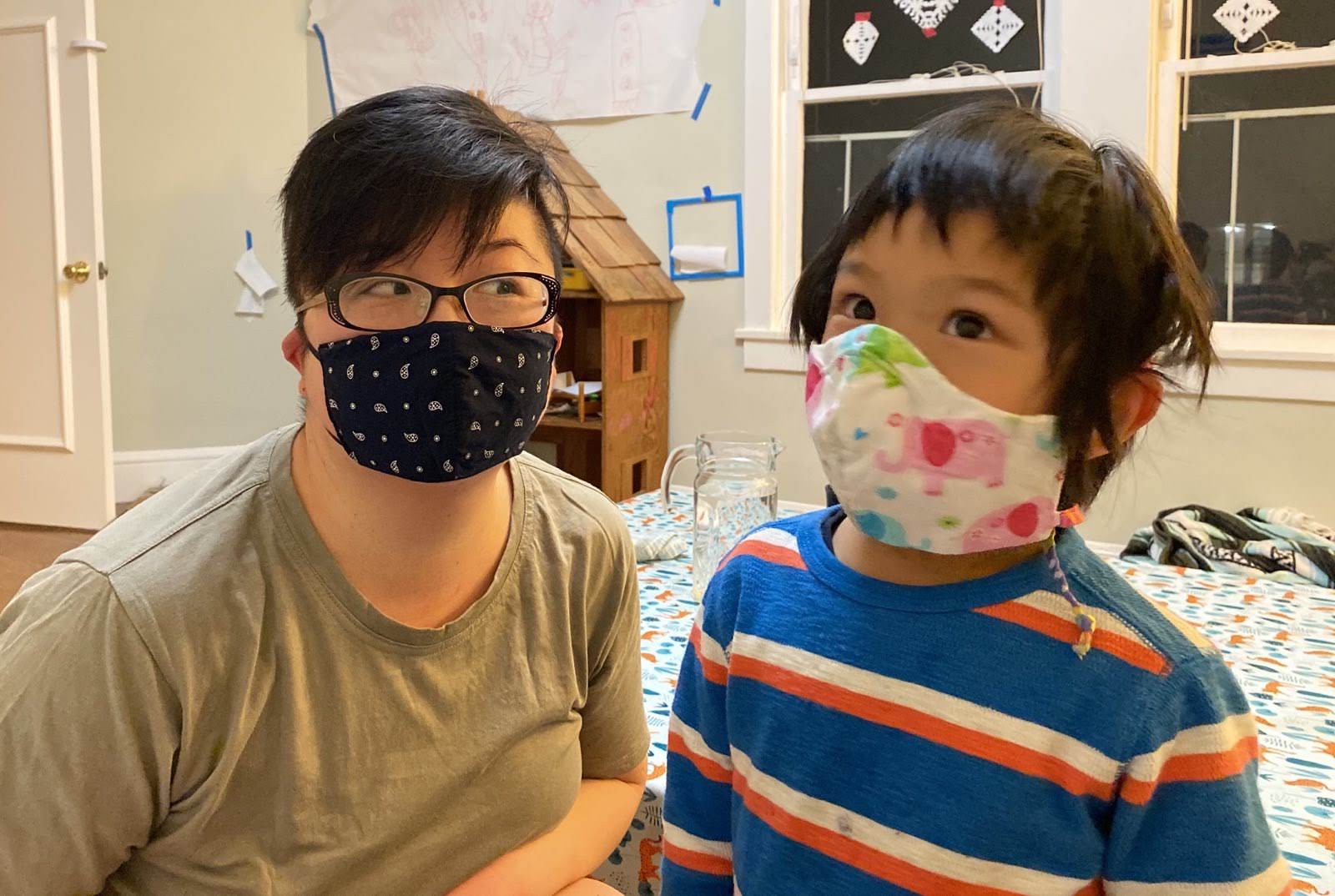 Short-haired East Asian American parent and young child with masks